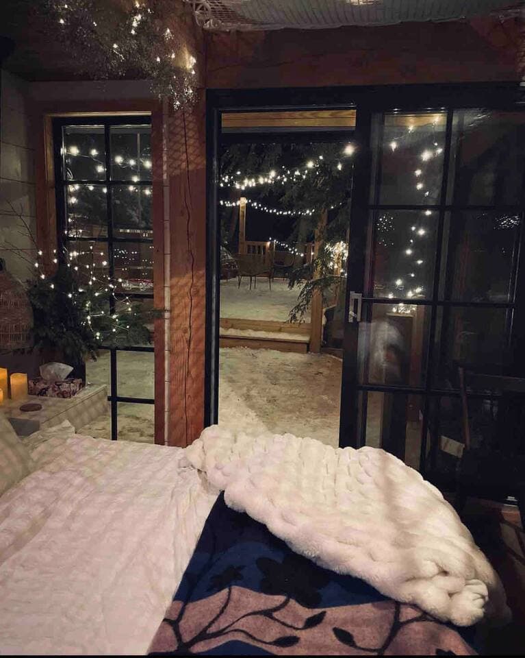 Bedroom doors open to a twinkling string-lit deck on a magical winter night.